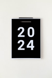A black calendar page with the year 2024 in large white numbers, hanging against a plain, light background.