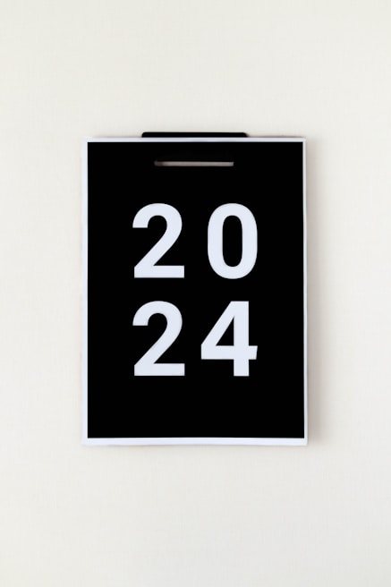 A black calendar page with the year 2024 in large white numbers, hanging against a plain, light background.
