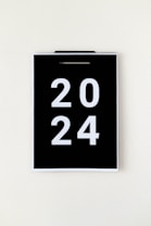 A black calendar page with the year 2024 in large white numbers, hanging against a plain, light background.