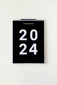 A black calendar page with the year 2024 in large white numbers, hanging against a plain, light background.