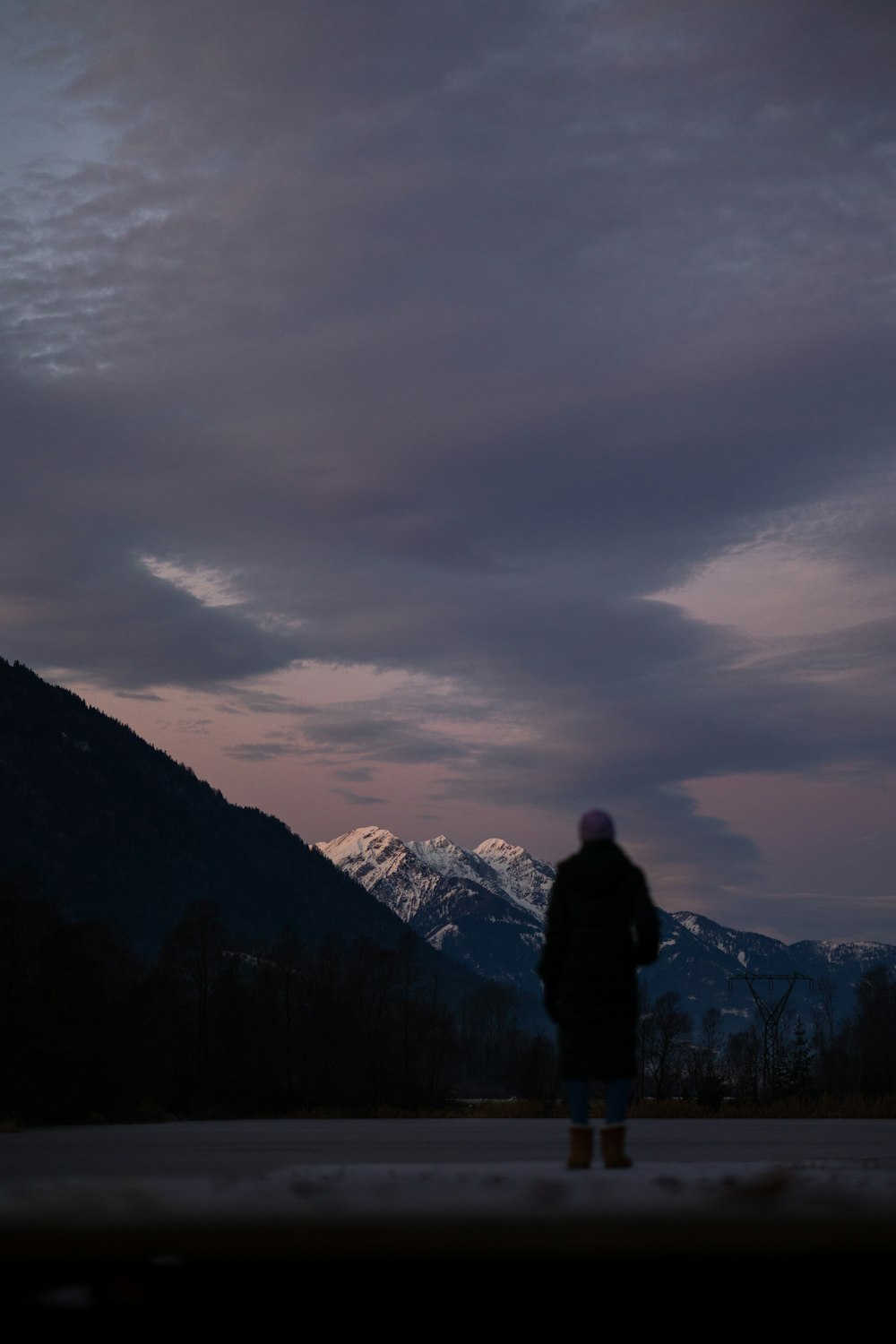 una persona in piedi davanti a una montagna al crepuscolo