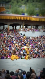 Traditional dancers performing in colorful attire amidst a festive village background.