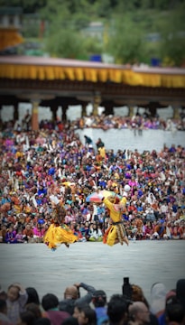 Traditional dancers performing in colorful attire amidst a festive village background.
