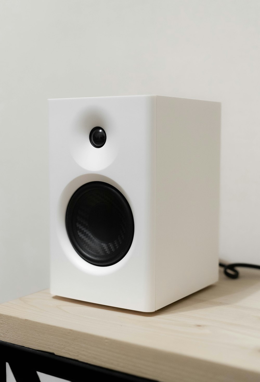 a white speaker sitting on top of a wooden table