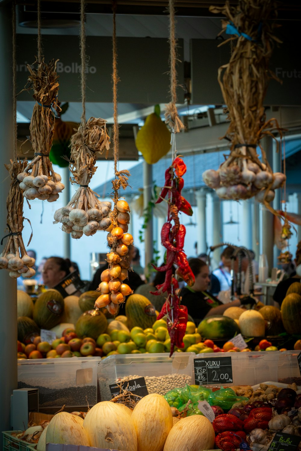 a fruit stand with hanging fruits and vegetables