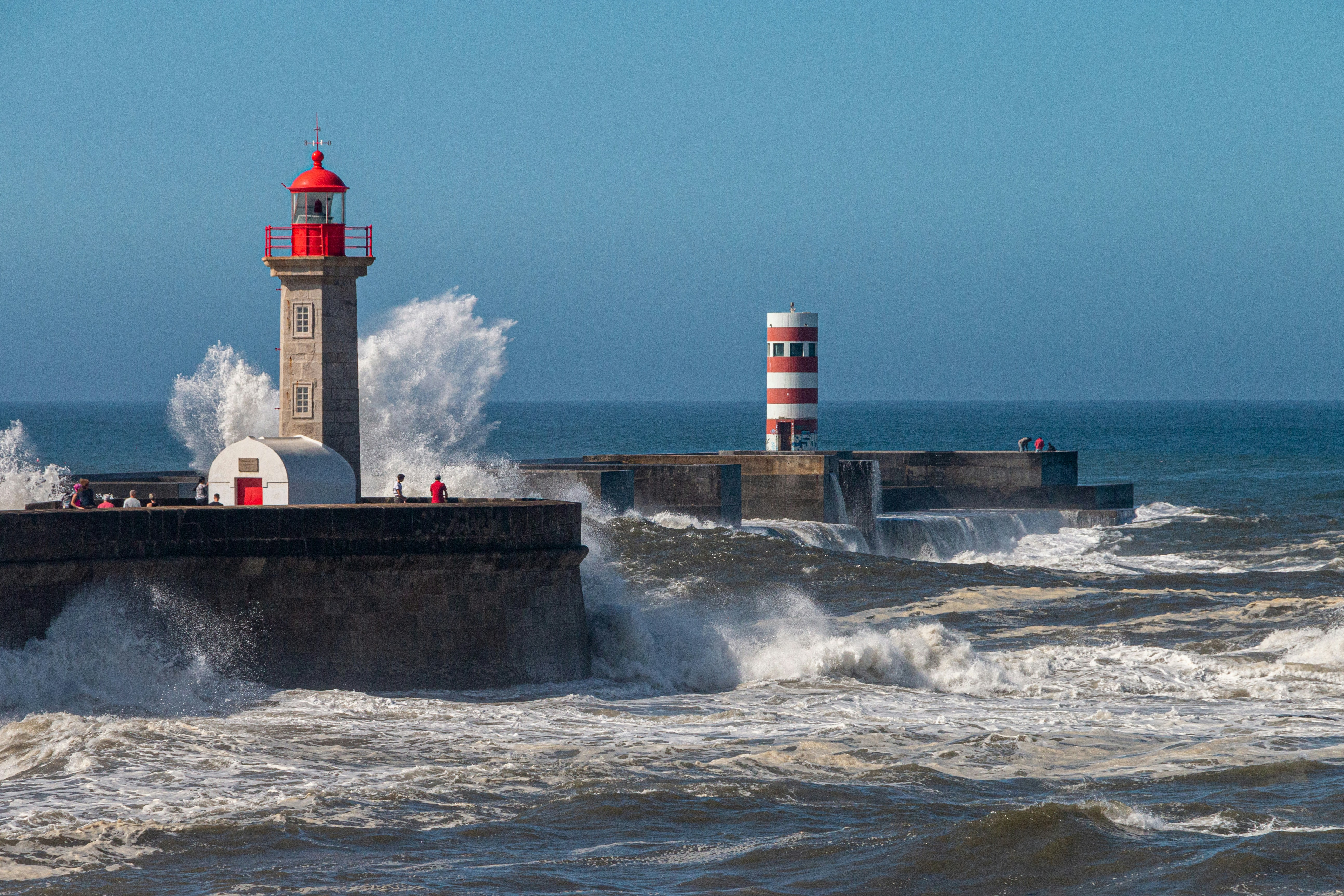 a lighthouse on a pier with waves crashing against it