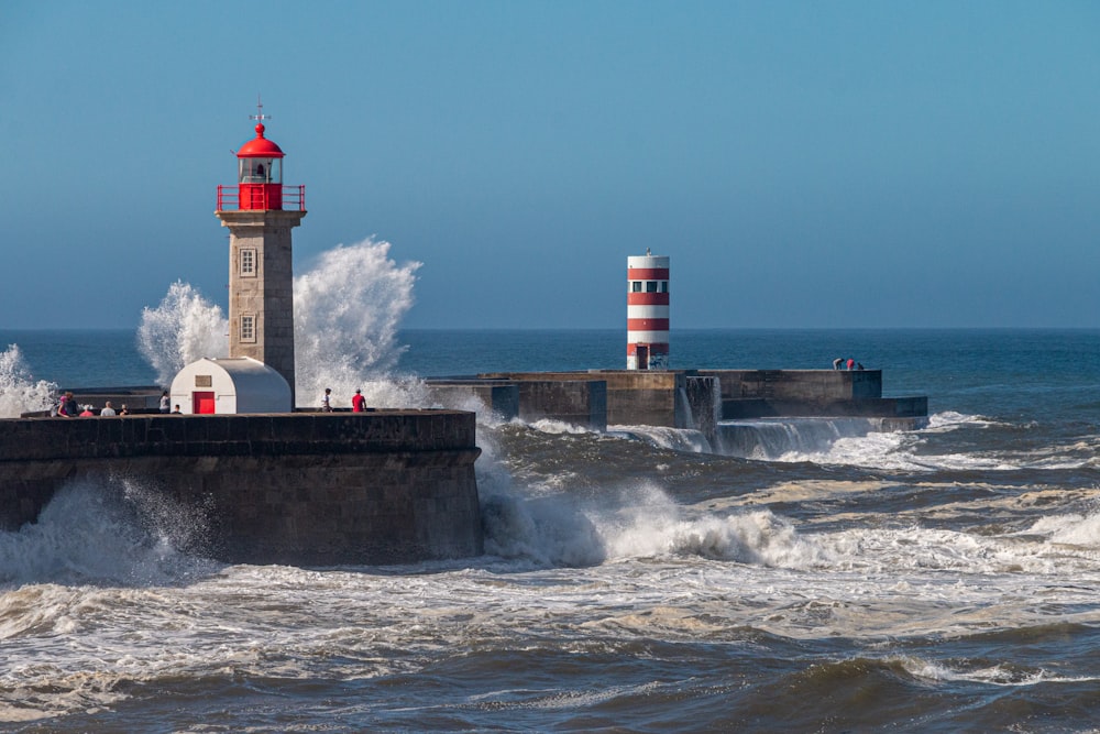 a lighthouse on a pier with waves crashing against it