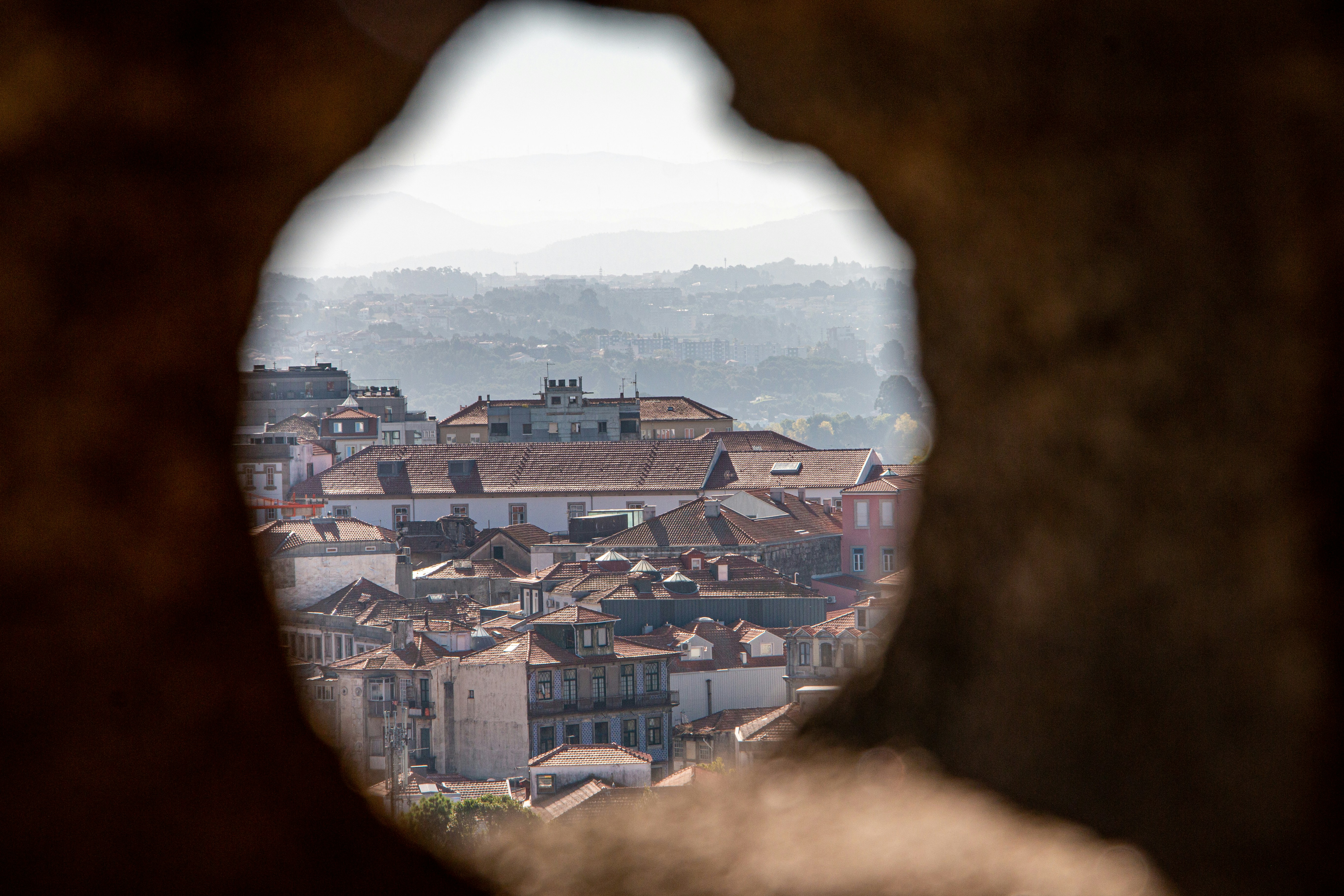 a view of a city through a hole in a rock