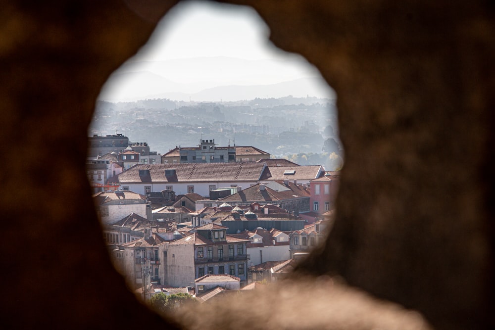 a view of a city through a hole in a rock