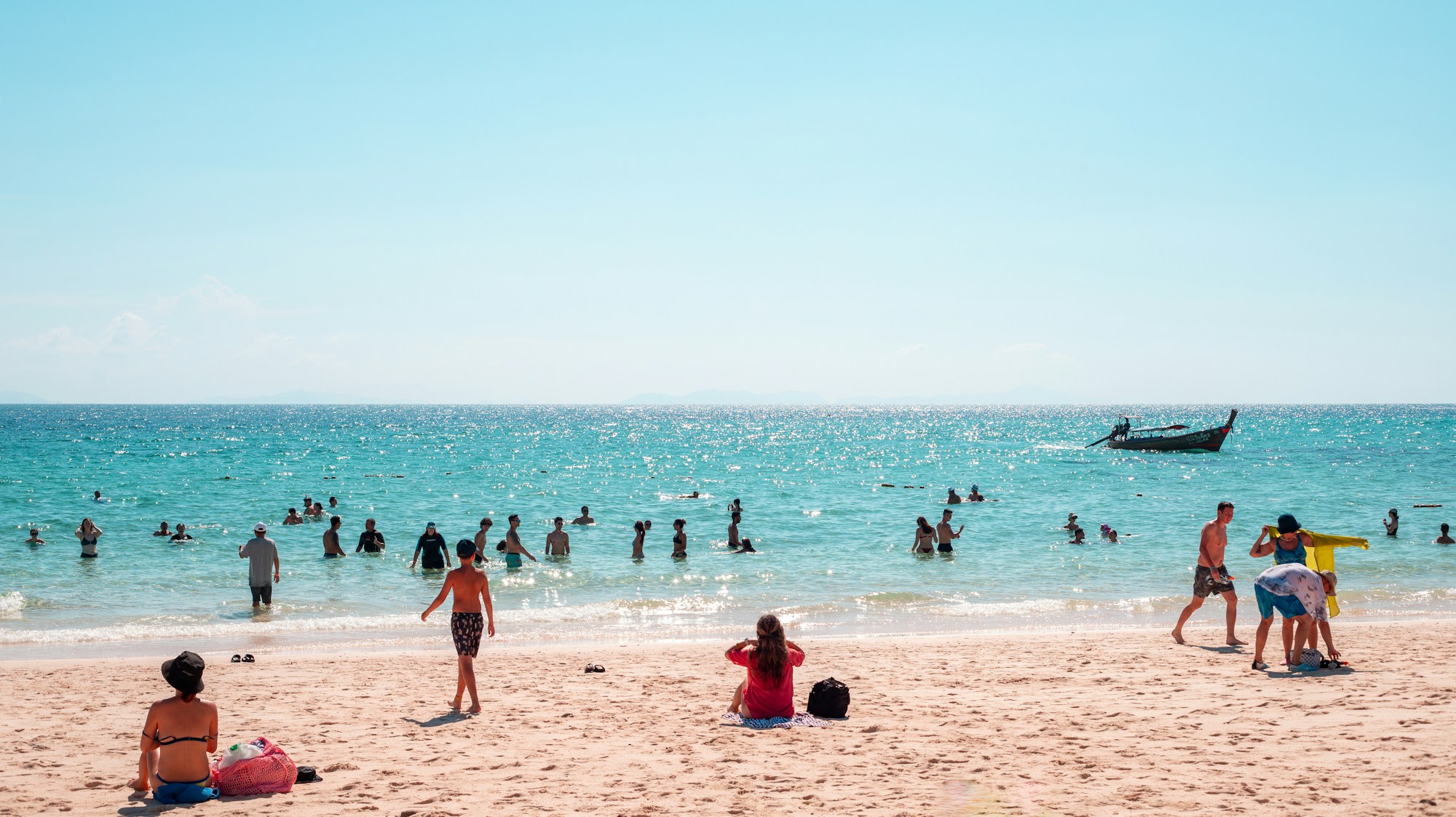 A long sandy beach with a boat on the horizon