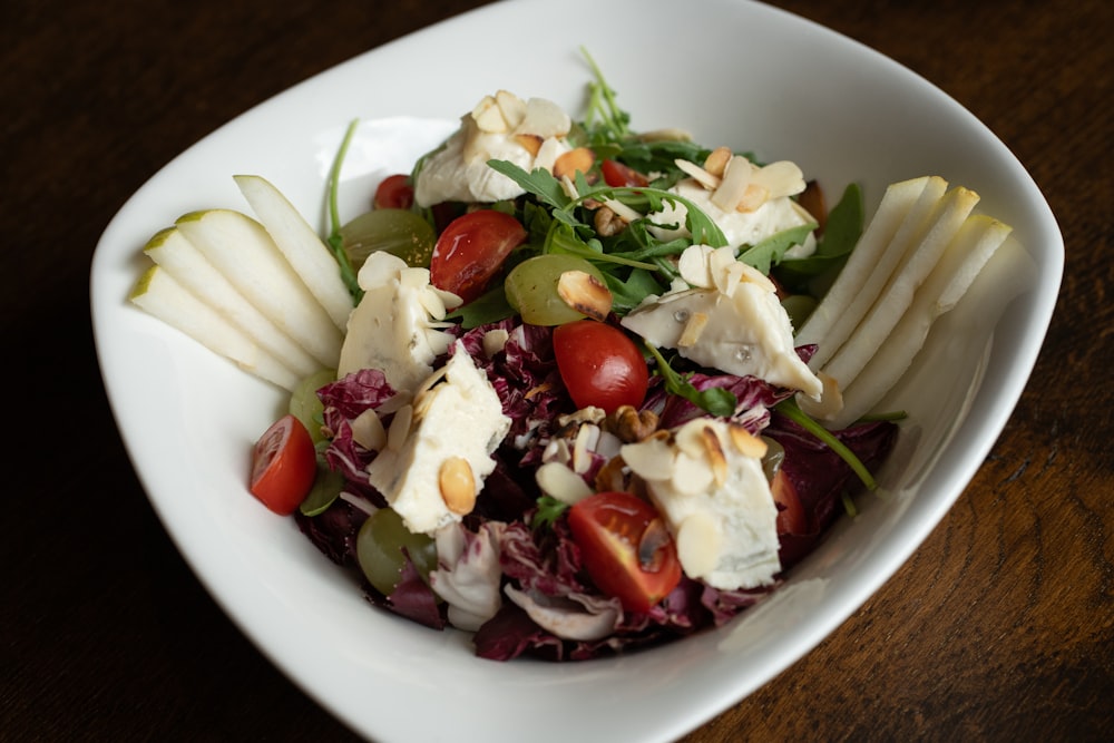 a salad in a white bowl on a wooden table