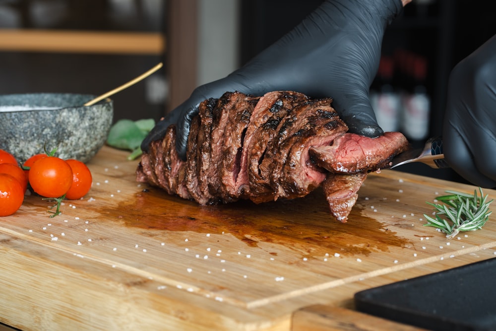 a person cutting up a piece of meat on a cutting board