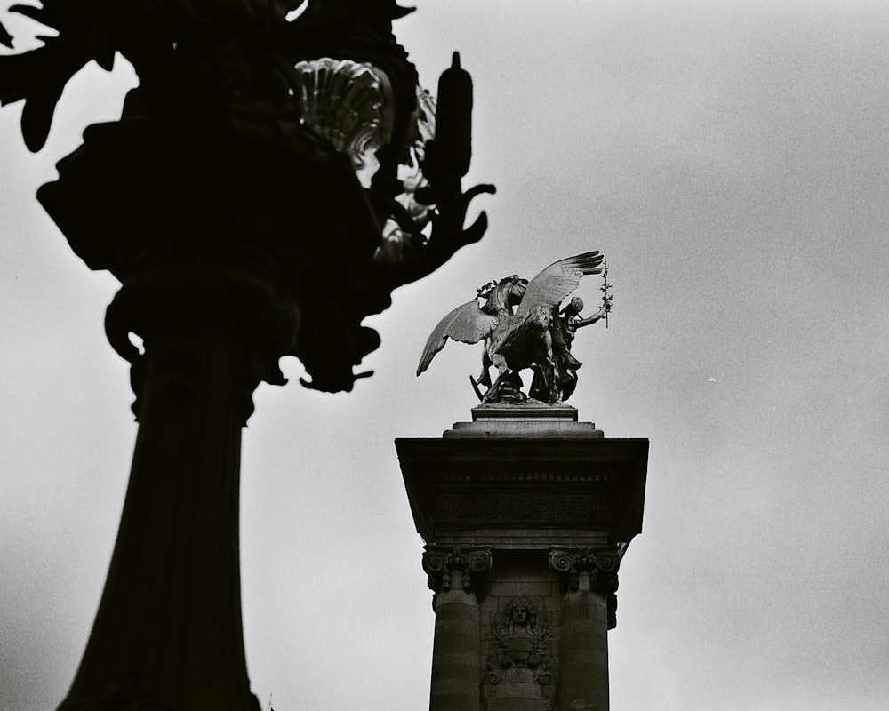 a black and white photo of a statue on top of a building