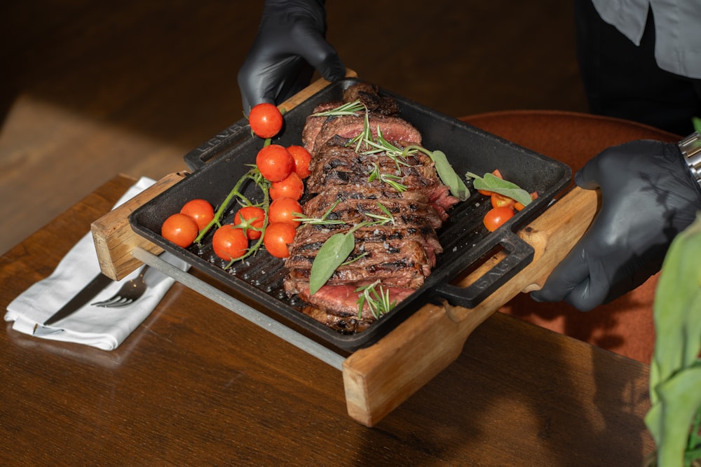 a person in black gloves holding a tray of food