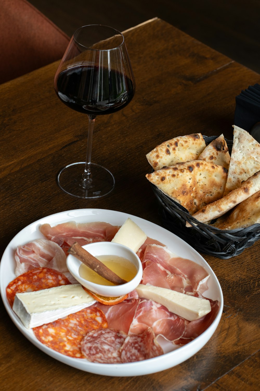 a plate of meat and cheese with a glass of wine