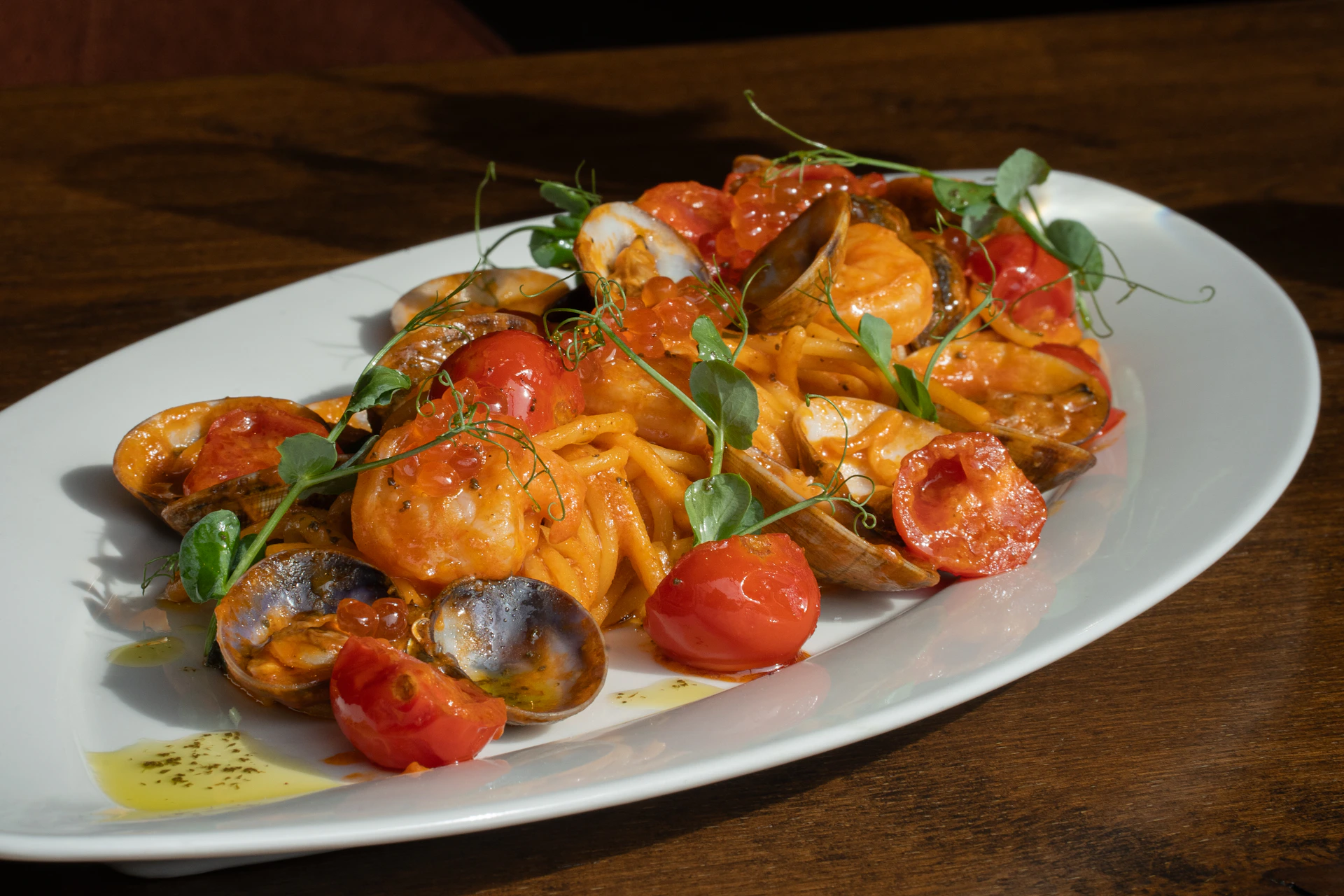 A vibrant seafood pasta dish with fresh shrimp and clams, garnished with herbs in a cozy restaurant setting.