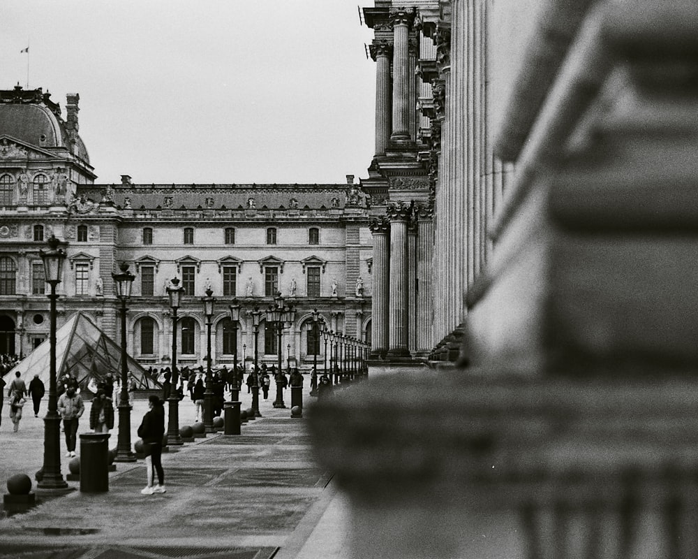 a black and white photo of people walking in front of a building