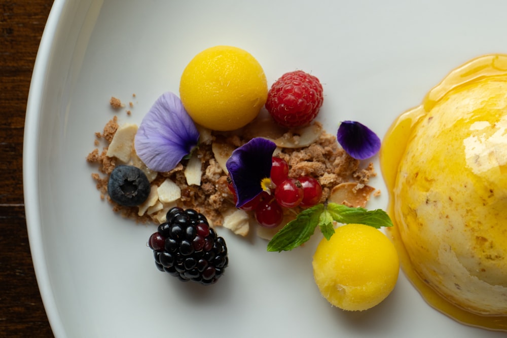 a white plate topped with fruit and a scoop of ice cream