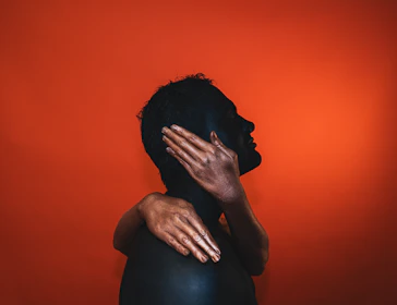 A silhouette of two figures entwined against a backdrop of rich velvet curtains, hinting at a passionate story.