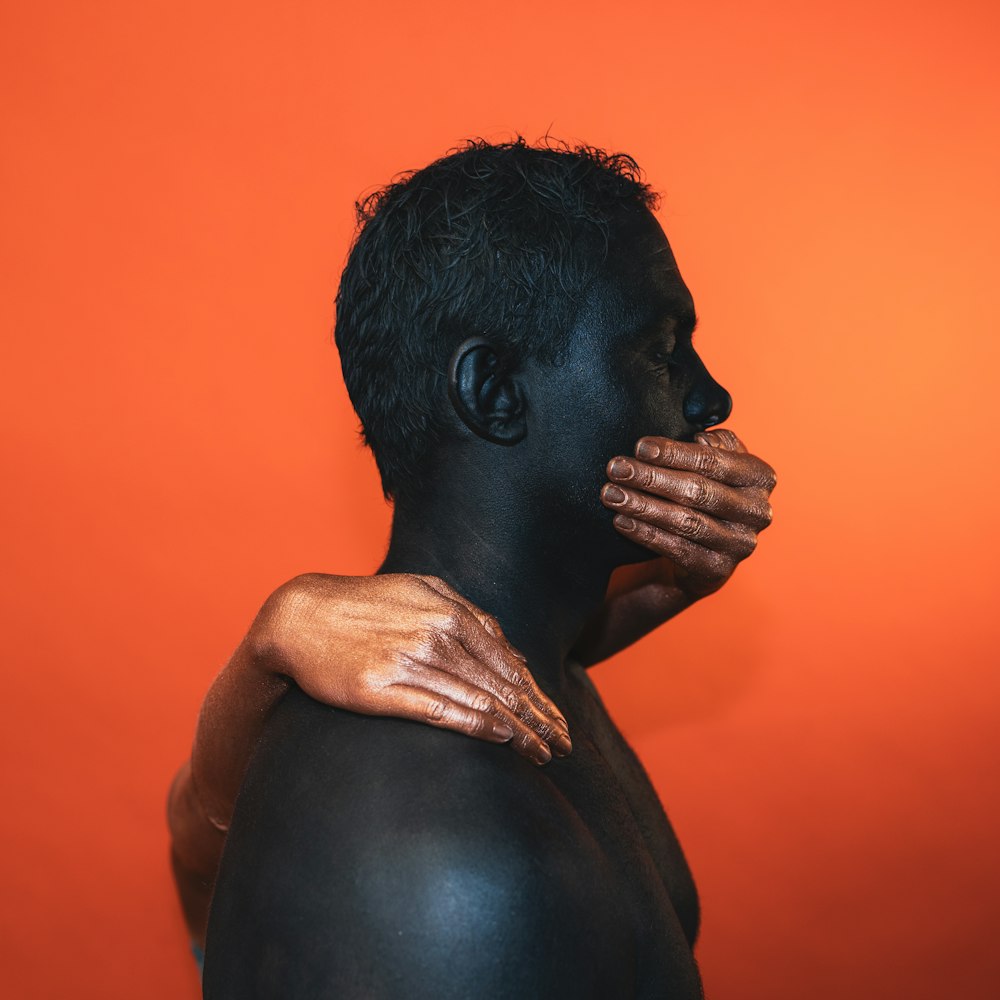 a man with painted hands covering his face