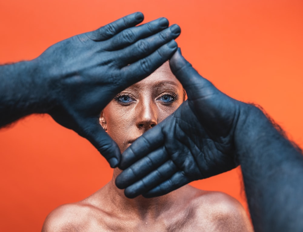 a woman wearing black gloves covering her face with her hands