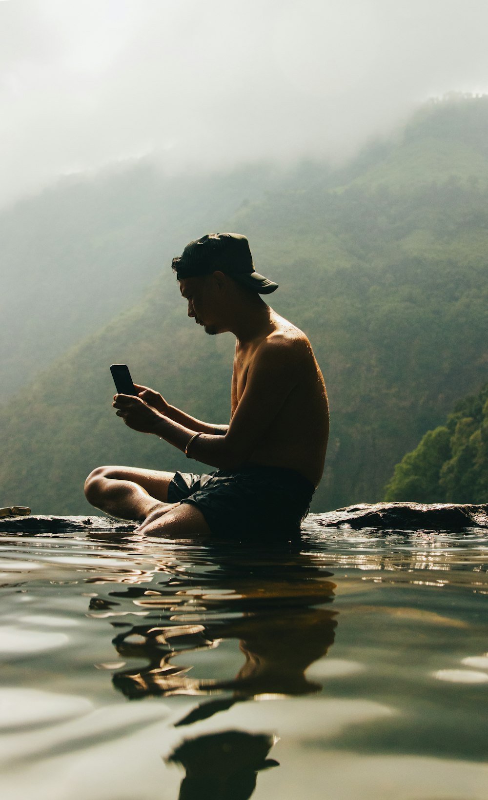 물 속에 앉아 핸드폰을 보고 있는 남자