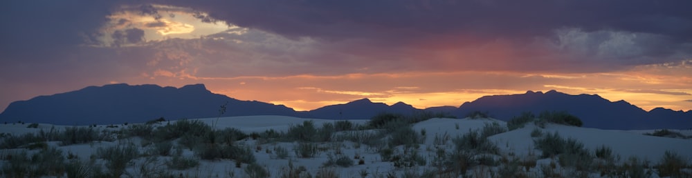 the sun is setting over the mountains in the desert