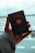 A hand is holding a German passport, which displays the emblem of the country. The background is blurred, possibly an airport or travel location, with a soft focus on the passport itself.