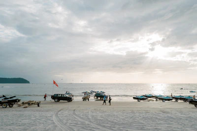 A group of happy riders preparing their jet skis on the sandy beach at sunrise.