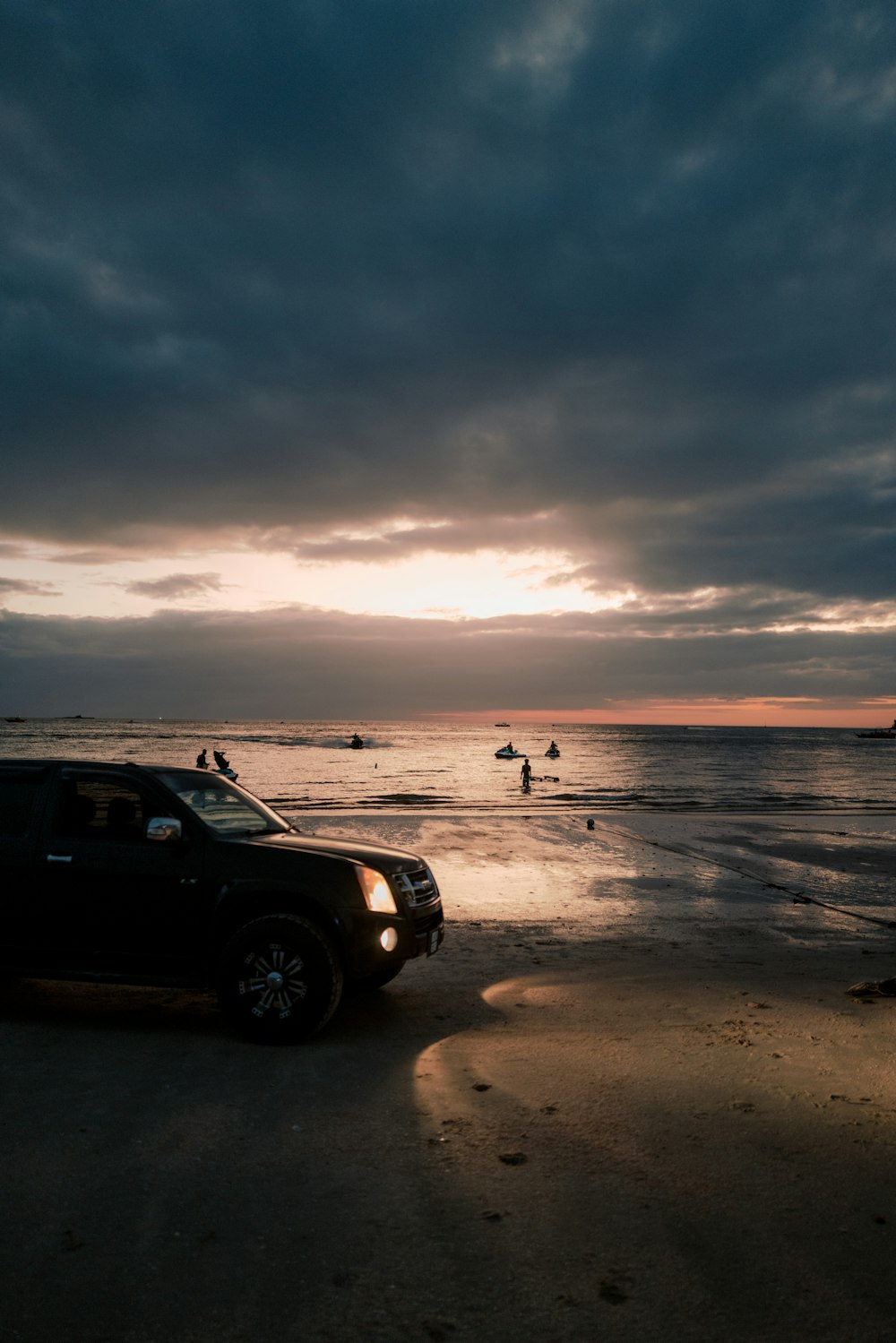 a truck parked on the beach at sunset