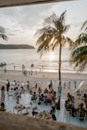 A vibrant beach club scene at sunset with lively guests and colorful decor.
