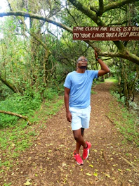 Close-up of a person taking a deep breath outdoors surrounded by green trees and fresh air.