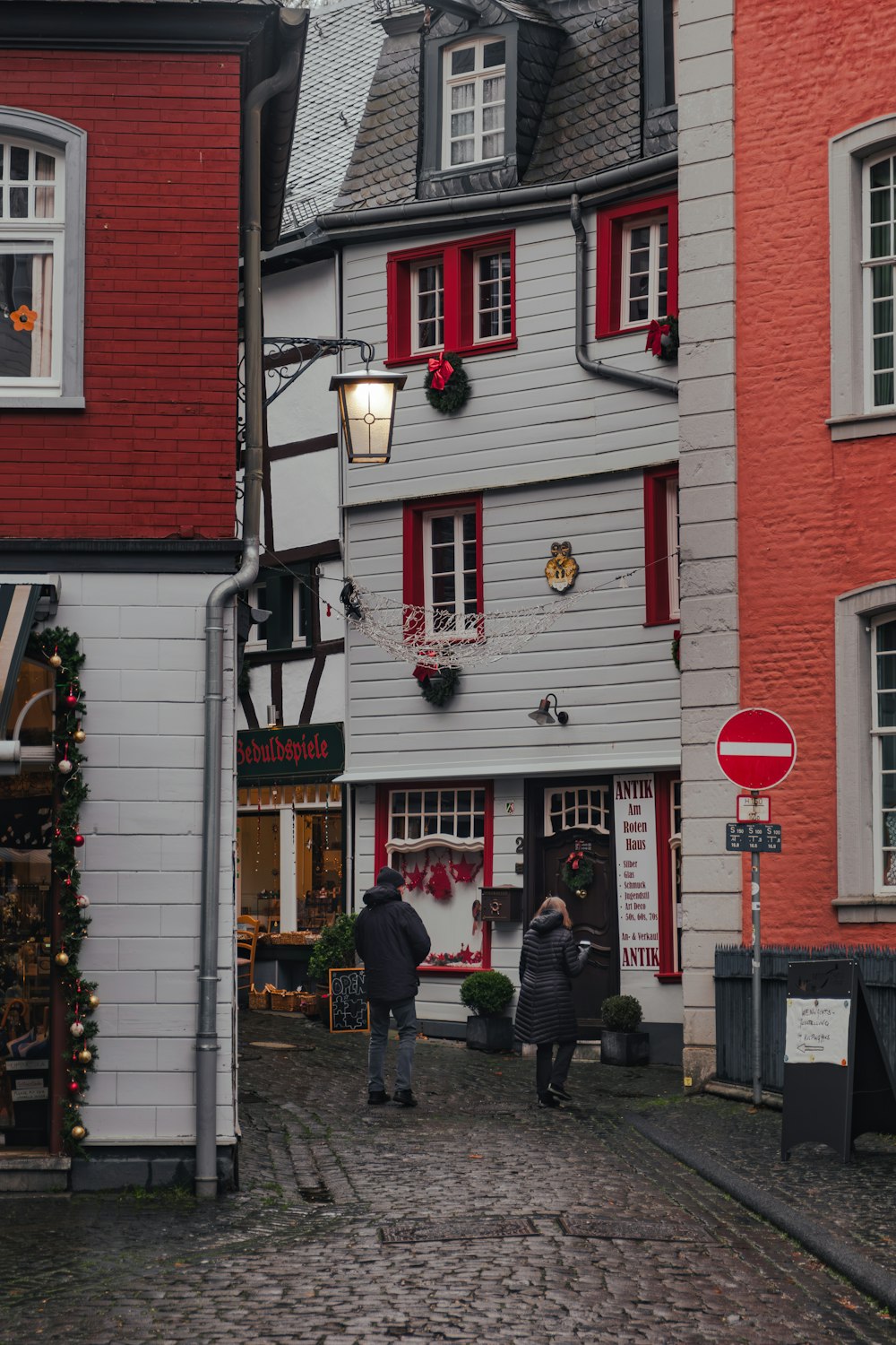 a couple of people walking down a cobblestone street