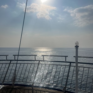 A serene deck view from a cruise ship with calm ocean waves stretching to the horizon