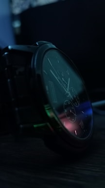 Close-up of a women's watch with a small round dial and milanese mesh strap glowing softly under warm light.