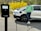 An enthusiastic woman managing an electric vehicle charging station with a bright smile.