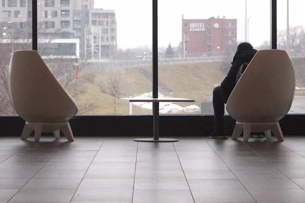 a person sitting on a chair in front of a window