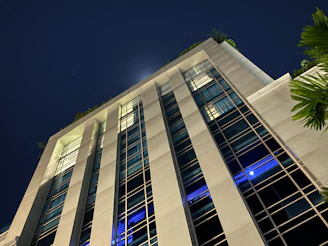 A high-rise building with a rooftop garden overlooking the city lights at night.