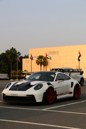 A sleek white luxury van parked near Muscat International Airport under a clear blue sky.
