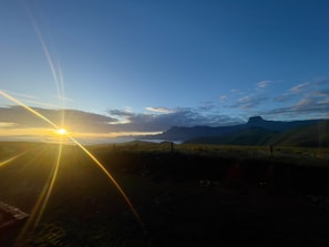 A scenic view of a sunrise over rolling hills and farmland.