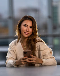 a woman sitting at a table looking at a cell phone