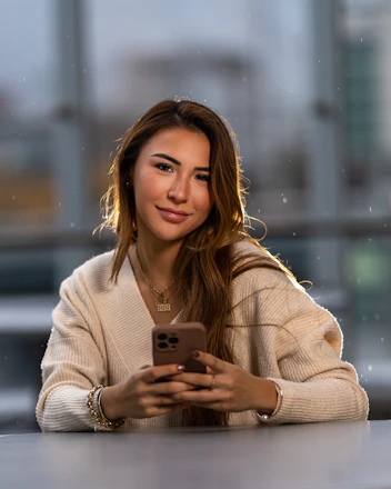 a woman sitting at a table looking at a cell phone