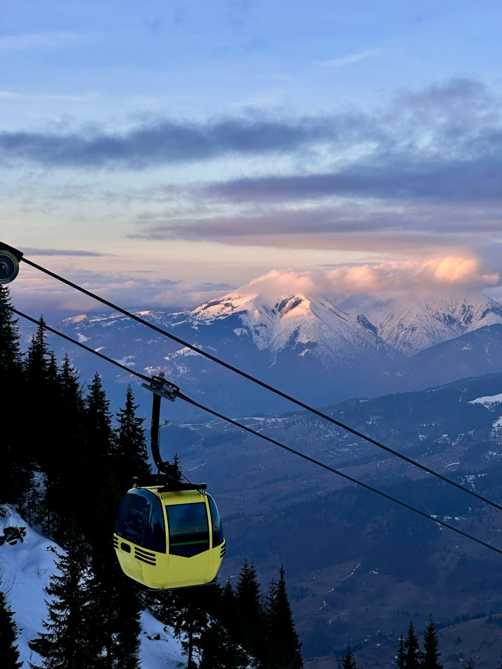 a yellow ski lift going up a snowy mountain