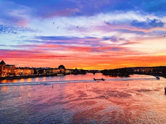 A vibrant sunset over Petrolina's São Francisco River with boats and palm trees silhouetted.
