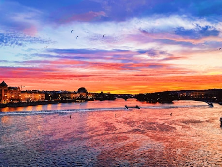 A vibrant sunset over Petrolina's São Francisco River with boats and palm trees silhouetted.