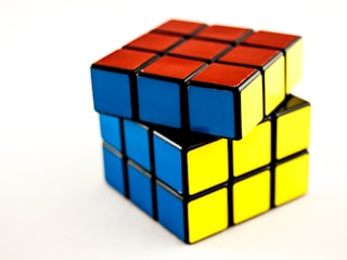 A partially solved Rubik's Cube with visible sides in red, blue, and yellow. The cube is positioned so that two layers are visible, creating an impression of a twist.