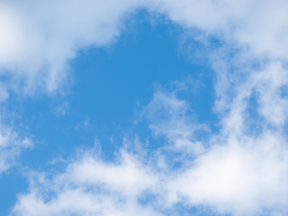 a plane flying through a cloudy blue sky