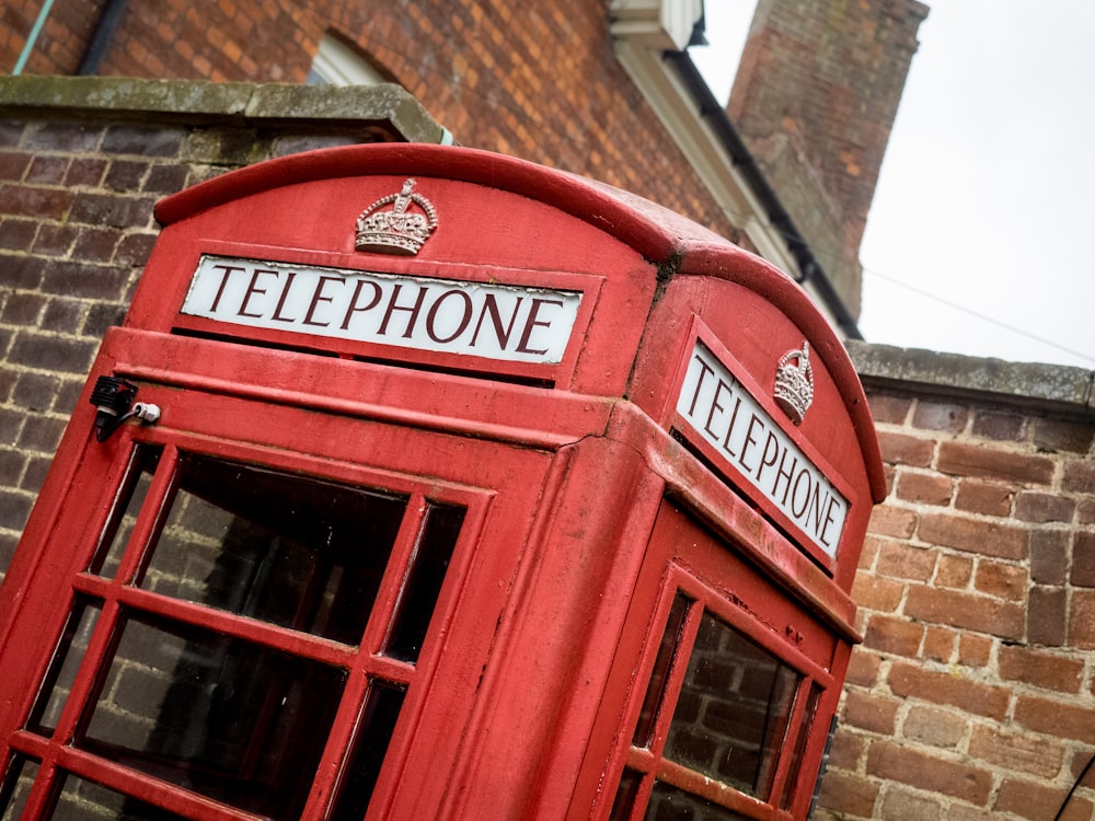 a red telephone booth in front of a brick building