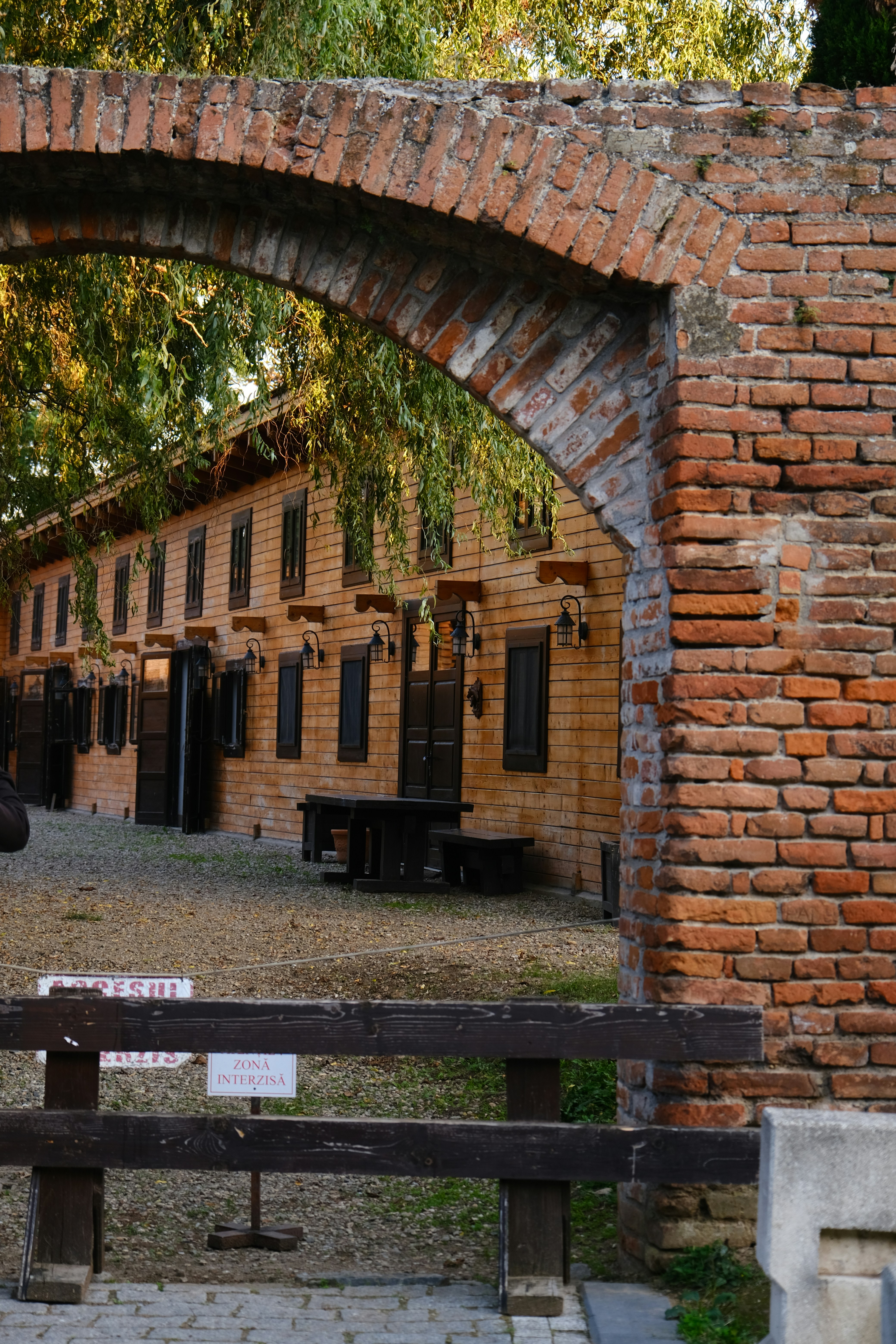 A person sitting on a bench in front of a brick building photo – Free