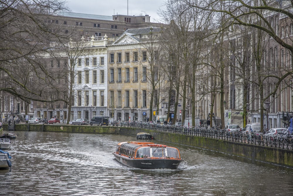 a boat traveling down a river next to tall buildings